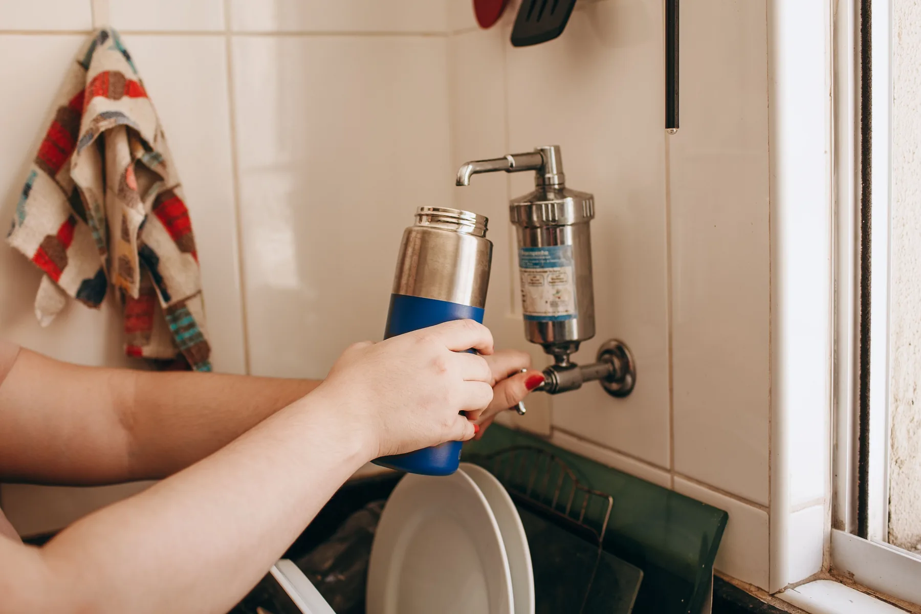 Person filling a bottle from a small water filter tap